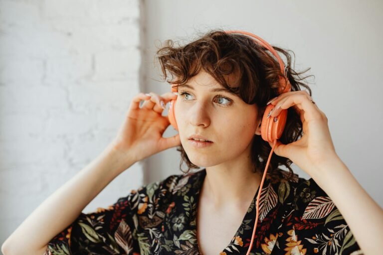 A woman wearing headphones and a floral shirt listens to music indoors.