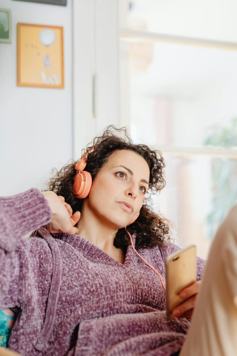 Cozy scene of a young woman enjoying music through headphones while relaxing indoors.