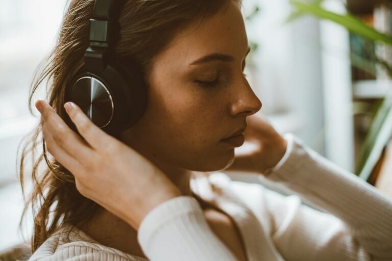 Side profile of a woman with headphones relaxing in a calm indoor setting.